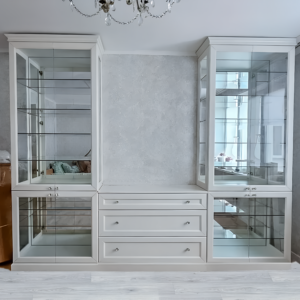 Белый шкаф в стиле неоклассика с стеклянными фасадами и выдвижными ящиками для гостиной